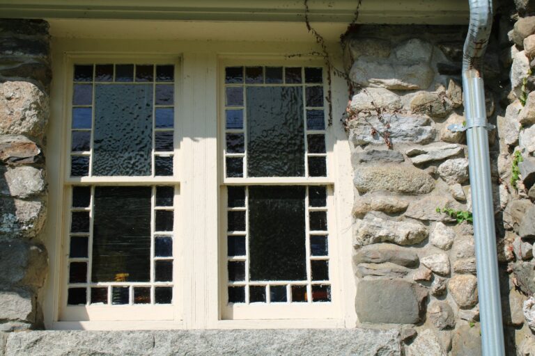 a stone building with two windows and a pipe