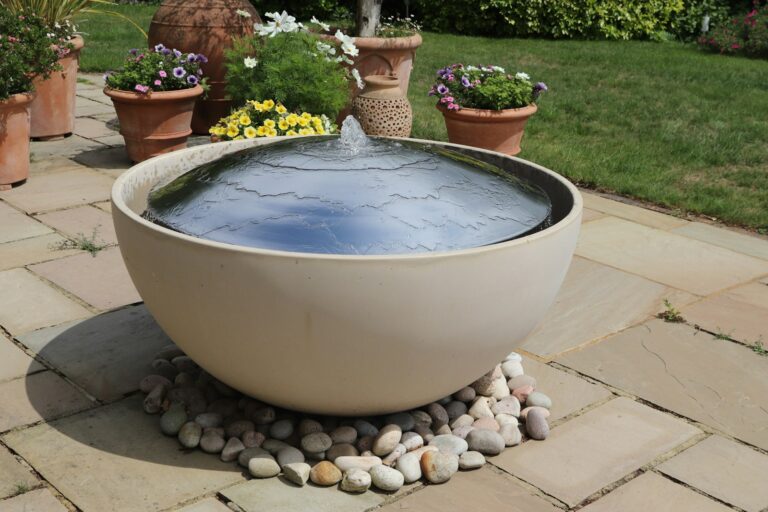 A modern water fountain sits in a garden setting.