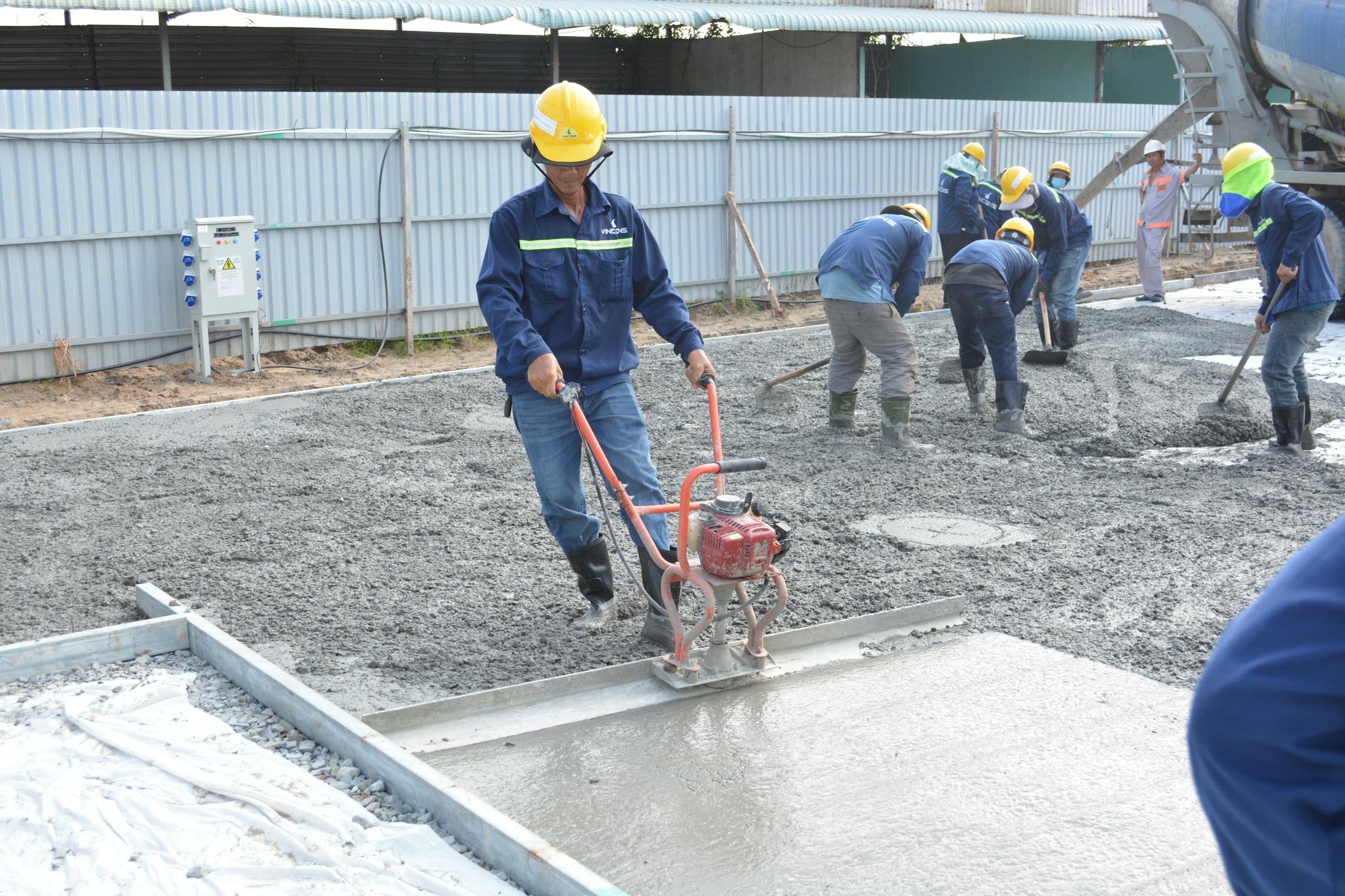 Estrich Boden – Arbeiter glätten frisch gegossenen Betonboden
