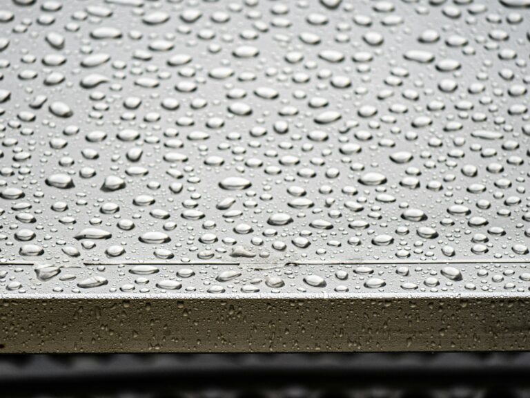 Schwitzwasser am Dach – Kondenswassertropfen auf einer kalten metallischen Oberfläche als Sinnbild für Kondensation an Bauteilen