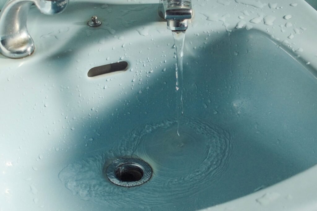 Abwasserrohr abdichten ohne Ausbau – Wasser fließt in den Abfluss eines Waschbeckens
