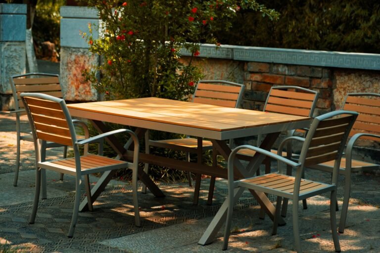 Akazienholz streichen: Das richtige Vorgehen Akazienholz streichen – Gartentisch und Stühle aus Holz auf einer Terrasse