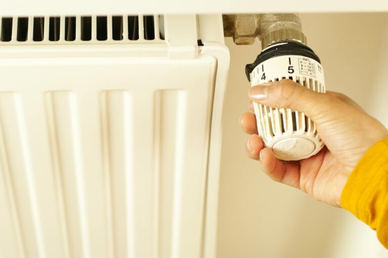 Heizungsventil wechseln ohne Wasser ablassen: So funktioniert es Heizungsventil wechseln ohne Wasser ablassen – Hand am Thermostat eines Heizkörpers