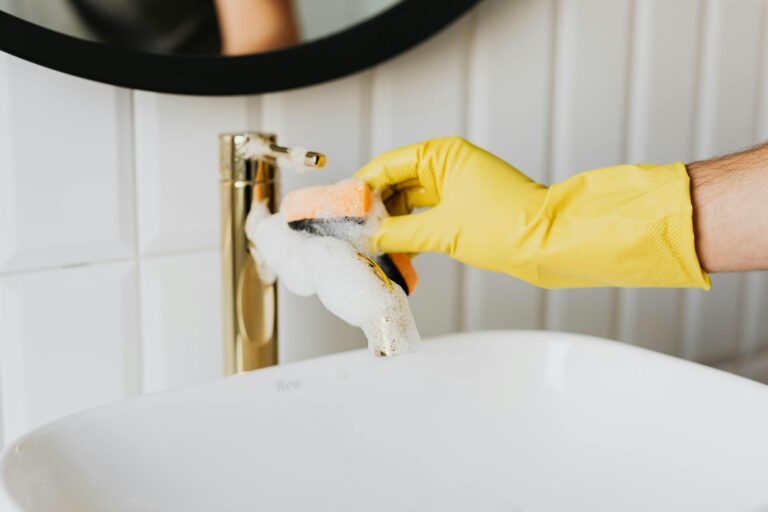 Wasserhahn lässt sich nicht zudrehen: Was du jetzt tun solltest Wasserhahn lässt sich nicht zudrehen – Person mit gelben Handschuhen am Wasserhahn