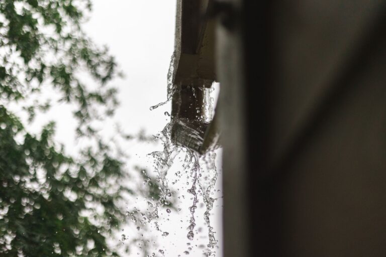 Dachrinne reinigen – Regenwasser läuft aus einer Dachrinne