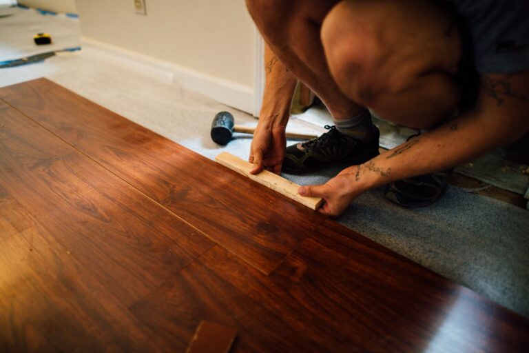 Laminat verlegen – Handwerker fügt Laminatdielen mit Schlagklotz zusammen