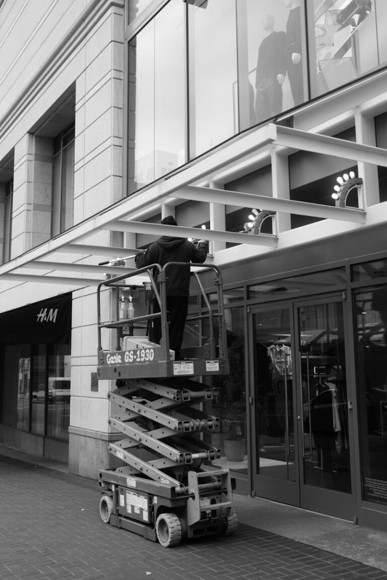 Worker on a scissor lift cleaning a store awning.