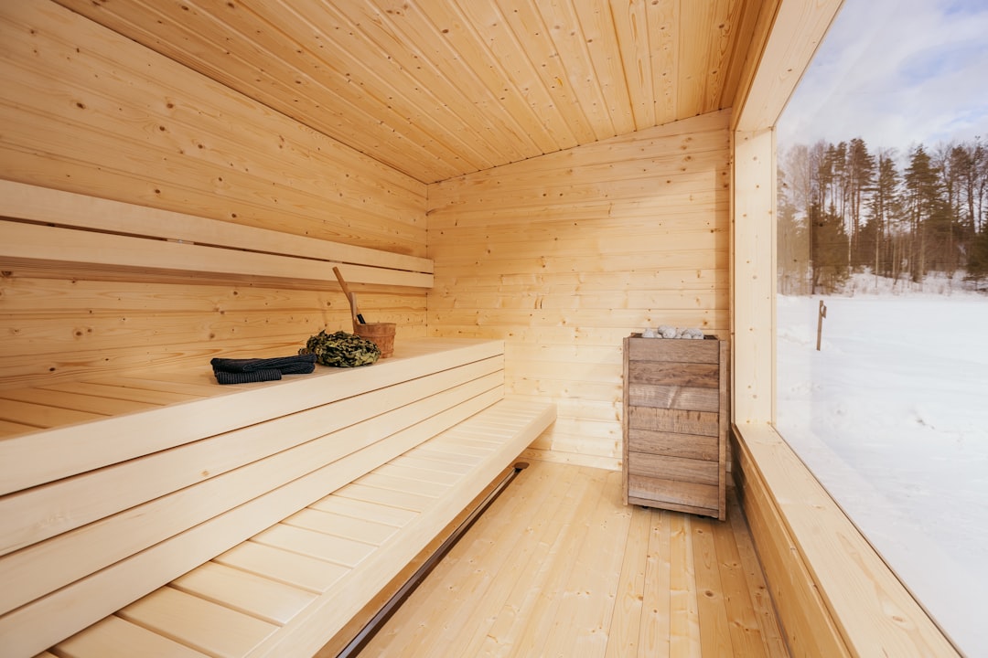 Gartensauna bauen – Innenraum einer Saunakabine mit Bank aus hellem Nadelholz und Saunaofen