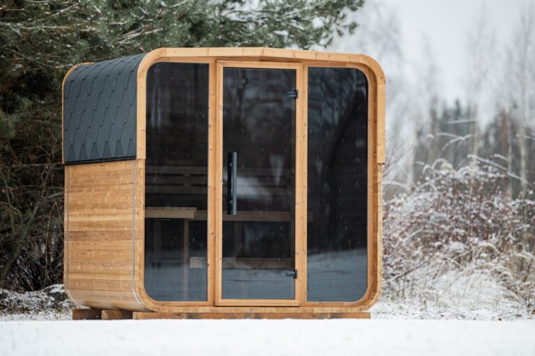 Gartensauna bauen: Was erlaubt ist und worauf es beim Aufbau ankommt Gartensauna bauen – freistehendes Saunahaus aus Holz mit großer Glasfront im Garten